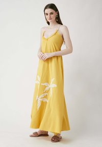 Gelbes Maxikleid mit dünnen Trägern, das mit weißer floralem Stickerei verziert ist. Leichter Stoff mit lässiger Passform und Fransenverzierung am Halsauschnitt.