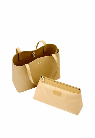 Velika torba iz rjave kože z dvema ročajema in ujemajoča se bež torbica z zadrgo, postavljena spredaj na belem ozadju.