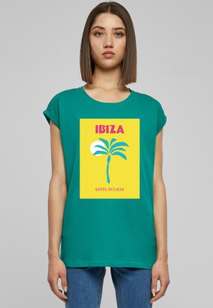 Türkises T-Shirt mit kurzen Ärmeln, das einen grafischen Druck mit gelbem Hintergrund, Palmenmotiv und dem Text "IBIZA SANTA EULALIA" zeigt.