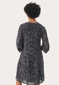 Marineblauwe bloemenjurk met lange mouwen en een elastische halslijn. Doorzichtige stof met lichte botanische patronen. Knie-lengte.