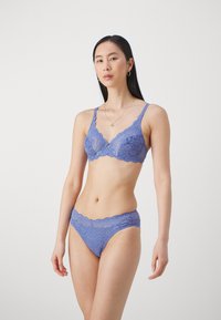 Spetsbustier och matchande trosor i mjuk lavendelblå. Har scalloperade kanter och delikata blommönster. Justerbara band för en perfekt passform.