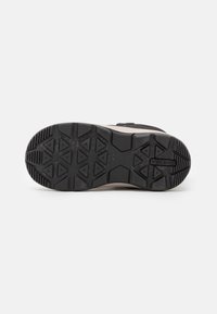 Suela de goma negra con un agarre con patrón. Entresuela marrón y parte superior del zapato negra con acentos texturizados en contraste. Área de puntera reforzada.