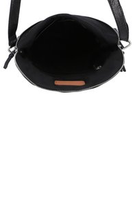 Indvendig i sort lædertaske med blød tekstur, lynlås og en brun læderdetalje. Rummelig med minimalistisk design.