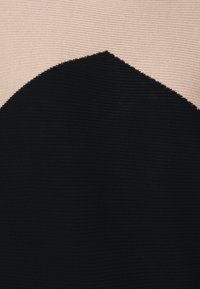 Black and beige ribbed knit fabric featuring a geometric design with a large black shape. Smooth texture; the colors create strong contrast.