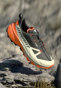 Ανδρικό παπούτσι τρεξίματος σε μονοπάτια με μαύρο άνω μέρος, πορτοκαλί λεπτομέρειες και υφασμάτινη σόλα για καλύτερη πρόσφυση. Ελαφρύ σχέδιο με σύστημα κορδονιών.