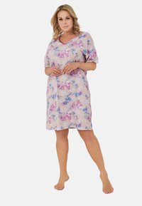 Kwiatowa nocna koszula uszyta z miękkiego materiału, z dekoltem w serek, krótkimi rękawami oraz wielokolorowymi wzorami różowych i niebieskich kwiatów na jasnym tle.