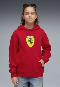 Sweat à capuche rouge en coton avec un grand logo Ferrari jaune sur la poitrine. Doté d'une poche avant et d'un ourlet côtelé avec un accent blanc sur la manche.
