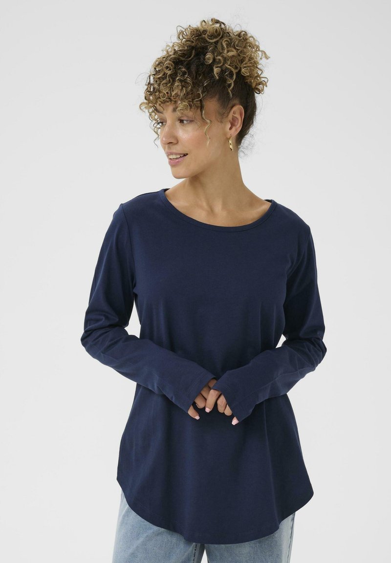 Maglietta a maniche lunghe color blu navy realizzata in un tessuto morbido, con un collo arrotondato e una vestibilità comoda. Presenta polsini leggermente svasati e un orlo curvo.