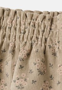 Tukaj je tan tkanina iz korduroja z teksturo nabrane tkanine, okrašena z rožnatimi in sivimi cvetličnimi vzorci po celotni površini. Mehka in rebrasta površinska podrobnost.