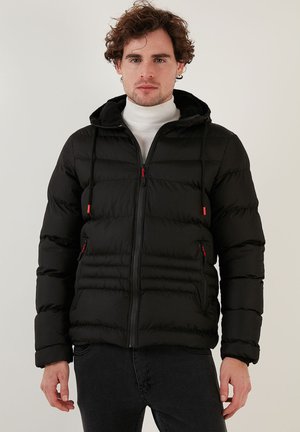 Sort pufferjakke med lynlås foran, elastiske ærmer, hætte med snore og røde detaljer. Glat tekstur med firkantet design.