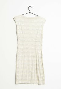 Robe mi-longue en tissu texturé de couleur beige clair, avec des rayures horizontales et de légères manches chauve-souris. Accrochée à un crochet noir.