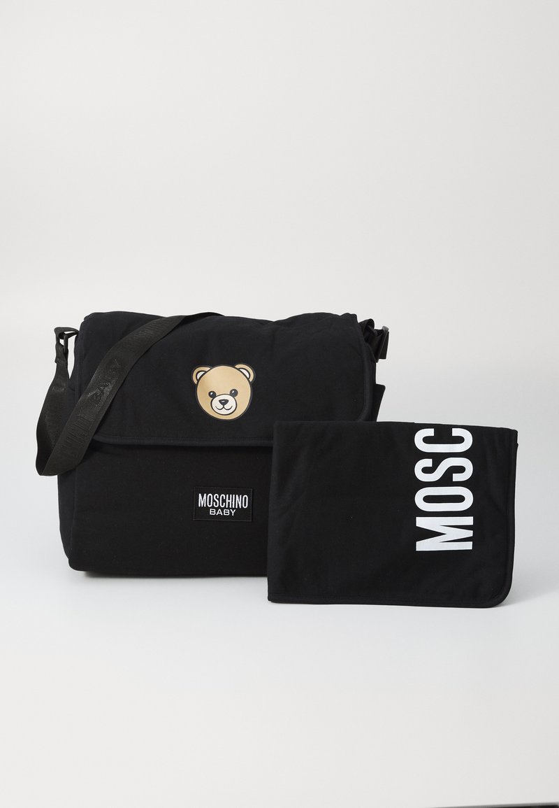 Melna Moschino Baby autiņbiksīšu soma ar lāču logotipu un atbilstošu melnu maināmo paliktni ar baltu "MOSC" tekstu uz vienkārša fona.