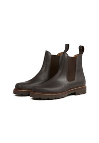 Bottes Chelsea en cuir noir avec panneaux élastiques sur les côtés, languettes de tirage et semelle texturée. Détails cousus le long du bord de la semelle.
