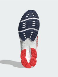 Die Laufsohle des Schuhs verfügt über eine strukturierten Gummibeschichtung in Marineblau, Rot und Weiß, die für Rutschfestigkeit ausgelegt ist, mit Rillen und Dämpfungselementen.