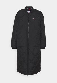 Abrigo largo negro acolchado con un diseño estructurado, que presenta un cierre con cremallera, un cuello redondeado y sutiles acentos metálicos.