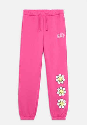 Pantaloni della tuta rosa con vita elastica e cordino, con logo bianco "GAP" e tre design di fiori sorridenti sulla gamba sinistra.