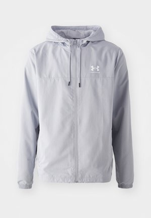 Light gray lightweight jacket with a hood, front zipper, elastic cuffs, and Under Armour logo on the left chest. Smooth, water-resistant material.