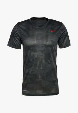 T-shirt noir à manches courtes Nike Dri-FIT avec un discret motif camouflage hexagonal et un petit logo rouge Nike Swoosh sur la poitrine.
