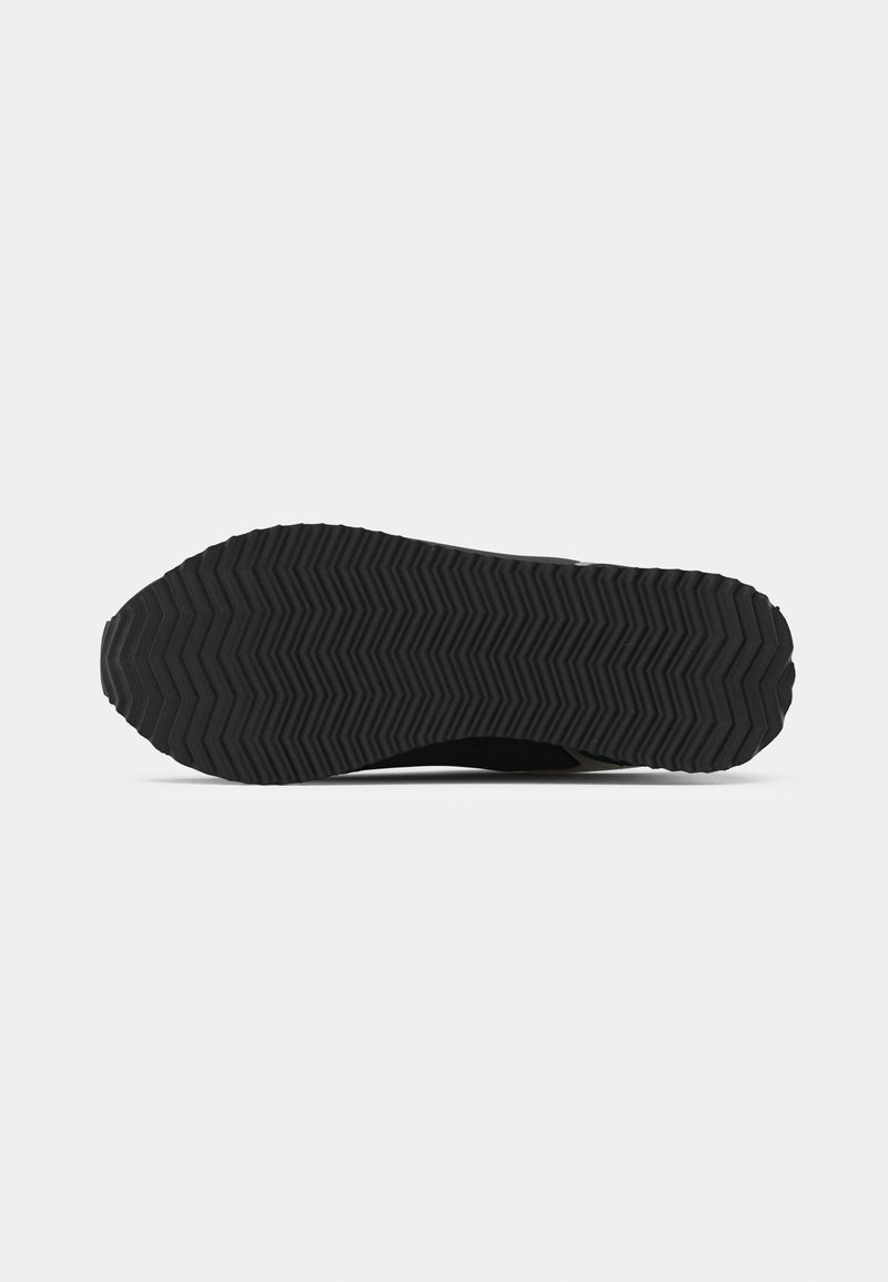 Schwarze Sneaker-Sohle mit tiefen Zickzack-Profilen für besseren Halt. Leichtes Material mit strukturierter Oberfläche. Keine sichtbaren Marken oder Verzierungen.