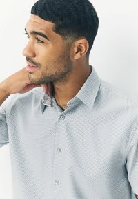 Grau karierte Hemd aus Stoff, mit einem Button-Down-Kragen, Vorderknöpfen und einem strukturierten Muster. Betont mit einem detaillierten Innenkragen.