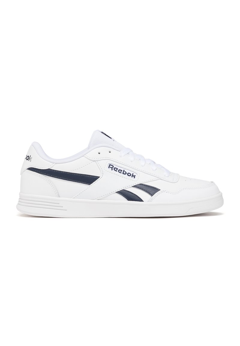 Zapatillas deportivas blancas con acentos en azul marino, textura similar a cuero, puntera redonda, diseño de cordones y logo de Reebok en el costado.