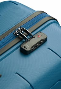 Valigia rigida blu con superficie testurizzata, doppia zip con hardware nero e lucchetto approvato TSA con tre dischi.