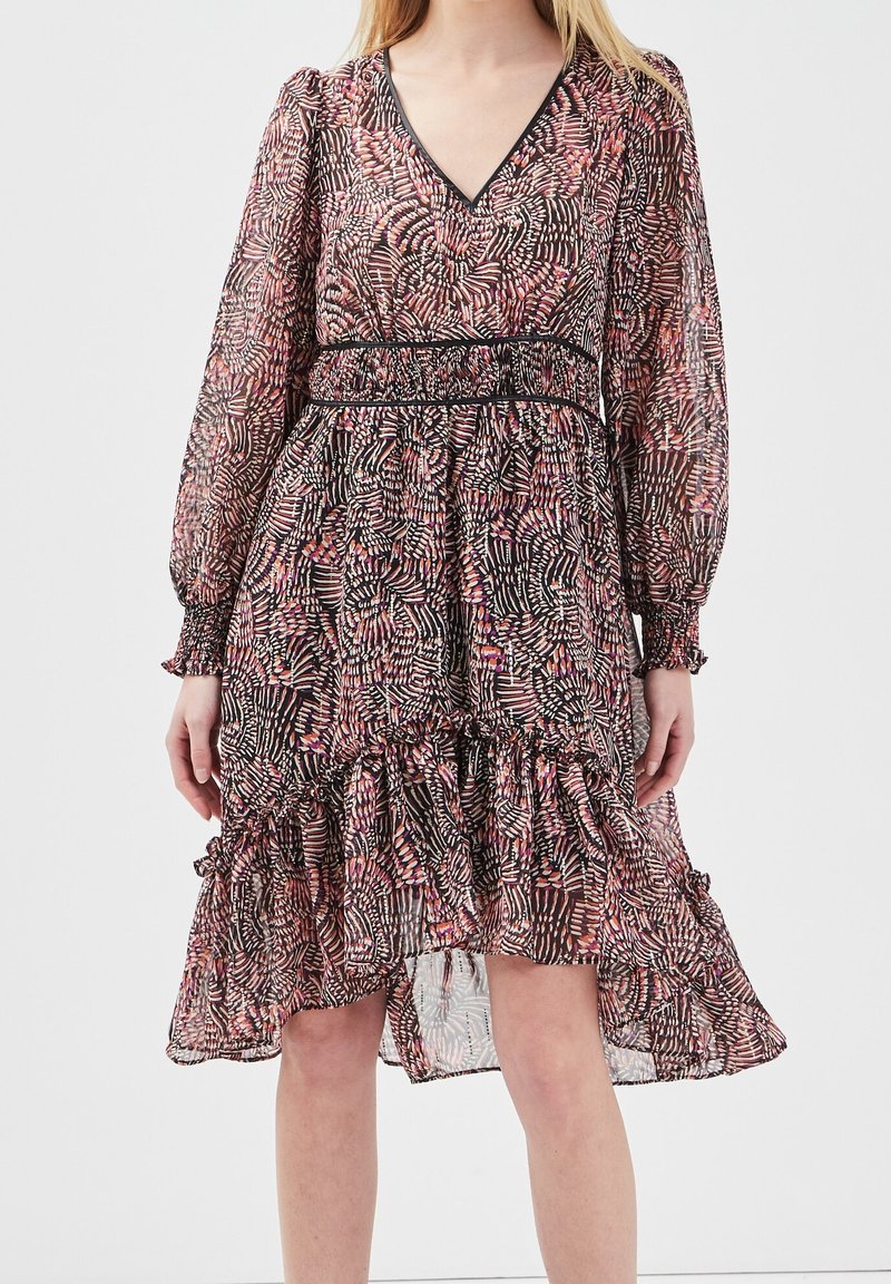 Robe noire et rose à motifs avec des manches longues, décolleté en V, smock au niveau de la taille et ourlet à volants. Tissu léger et transparent avec texture.