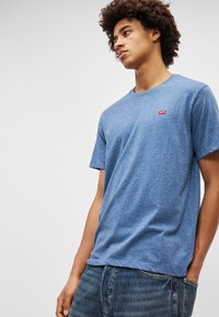 Sinine helesinine lühikeste varrukatega t-särk, mis on valmistatud pehmest puuvillast, ümmarguse kaelusest ja väikese punase Levi'si logoga vasakul rinnal.