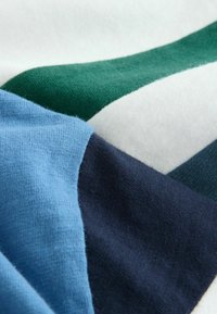 Bavlnená látka s diagonálnymi sekciami v svetlomodrej, tmavomodrej, bielej a zelenej farbe. Mäkká textúra s hladkým povrchom.