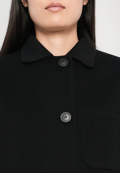 Black wool blend coat featuring a collar, front buttons, and a chest pocket. The fabric has a soft, textured appearance.