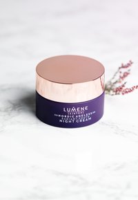 Pot violet de la crème de nuit Lumene Nordic Ageless, avec un couvercle en or rose réfléchissant, une texture lisse et des détails imprimés sur le corps.
