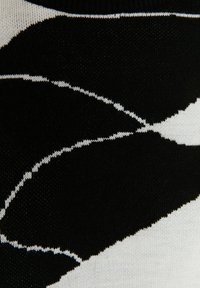 Tissu tricoté noir et blanc avec un motif abstrait et incurvé ressemblant à de grands pétales ou feuilles.