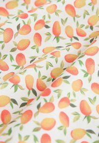 Tejido con un fondo blanco y un patrón repetido de mangos naranjas y amarillos junto a hojas verdes, con una textura suave.