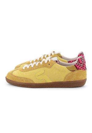 Paire de baskets basses jaunes avec lacets blancs, détails en daim, semelles marron et panneaux de talon à motifs roses.