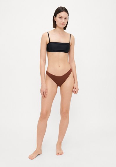 Musta bandeau-bikini yläosa ohuilla hihnoilla yhdistettynä ruskeisiin korkeavyötäröisiin bikinialushousuihin; sileä kangas, minimalistinen muotoilu, saumattomat reunat.