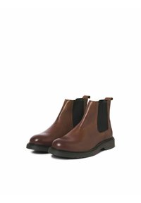 Bottines Chelsea en cuir marron avec panneaux latéraux élastiques et onglets de traction. Semelle en caoutchouc plate avec un motif de traction subtil. Finition lisse et design épuré.