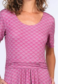 Kleid mit kurzen Ärmeln aus pinkem Stoff, das ein zartes weißes Blattformmuster aufweist. Es hat einen runden Ausschnitt und eine geraffte Taille für zusätzliche Textur.