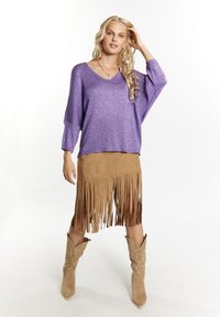 Violet blizgučiais megztinis su plačia iškirpte, derinamas su šviesiai rudomis zomšo sijonu su frangėmis ir šviesiai rudais kaubojiškais batais.