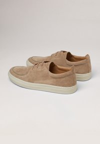 Chaussures en suede beige clair avec un embout arrondi, fermeture à lacets et semelle en caoutchouc crème. Comprend des détails de couture et un logo embouti sur le talon.