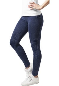 Navyblå leggings med en slät textur som har ribbade detaljer vid låren och en figurnära design, kombinerade med vita sneakers.