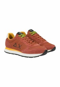 Sneakers rossi in suede con accenti neri, stringhe verdi e una suola bianca e gialla. Presentano un logo e un design testurizzato sui lati.