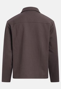 Camisa marrón con cuello, tejido texturizado, mangas largas, corte recto, vista trasera, superficie con patrón sutil, sin accesorios ni elementos visibles.