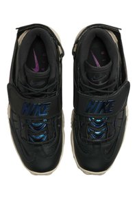 Svarta Nike-sneakers med ovandel i läder och glansigt blått accent, vadderad krage och en kringgående kardborreband. Transparent yttersula synlig.