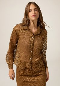Brown lace blouse with a button-down front, long balloon sleeves, and intricate floral patterns. Sheer fabric with a soft texture.