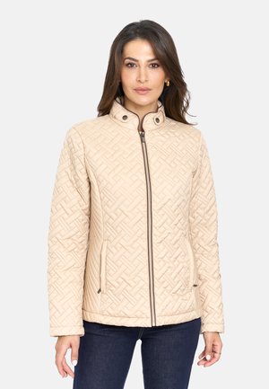 Chaqueta acolchada beige con un cuello alto, que cuenta con una cremallera frontal, bolsillos laterales y un patrón texturizado. Detalles oscuros en la cremallera como acento.
