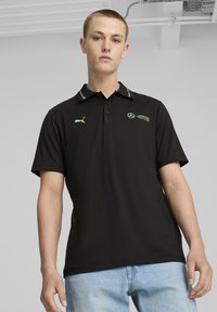 Sort polo-shirt med en kontrastfarvet krave med grønne detaljer, logo-broderi og korte ærmer. Fremstillet af glat, åndbart stof.