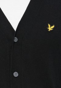 Black cardigan with a V-neck, made of knitted material, featuring a yellow eagle logo and six dark buttons down the front.