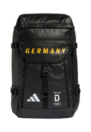 Schwarzer Rucksack mit gelbem "GERMANY"-Schriftzug, Adidas-Logo und Team-Germany-Olympiaemblem auf der Klappe der Fronttasche.