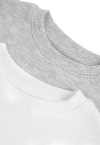 Tre crewneck t-shirts i vitt och ljust grått. Den vita skjortan har en slät yta, medan den grå har ett subtilt ribbat mönster.