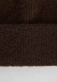 Gorro de punto marrón con un acabado texturizado, que presenta un puño acanalado y un material de lana suave y pelusa.